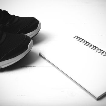 running shoes and notepad on white wood table black and white tone color style