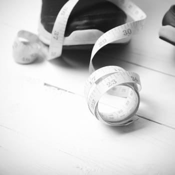 running shoes and measuring tape on white wood table black and white tone color style