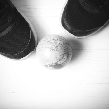 running shoes and earth ball on white wood table concept world healthy black and white tone color style