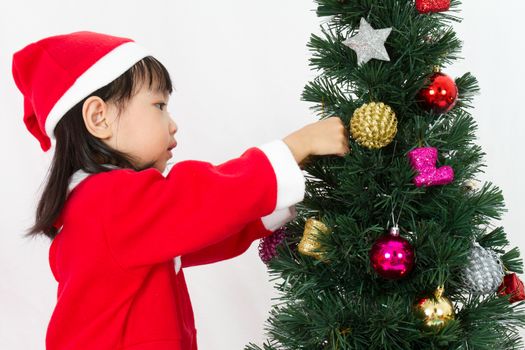 Asian Chinese little girl posing with Christmas Tree on plain white background studio.