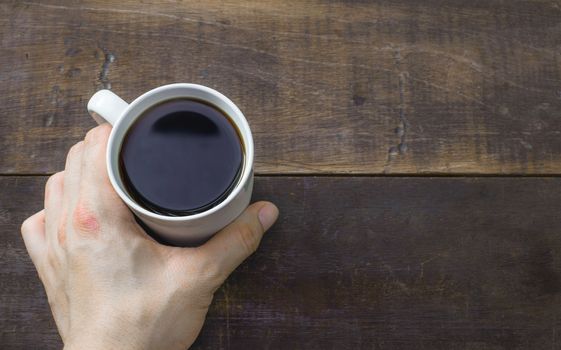 hot coffee in man hand on wood table