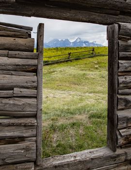 Looking through an old cabin window at the  Grand Tetons National Park, Wyoming.