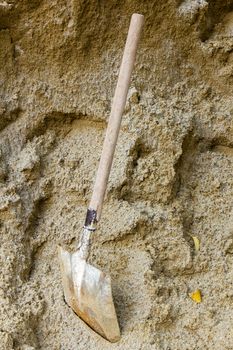 Shovel stick on the sand near the construction site.