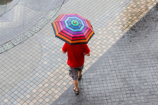 A man walking in the rain with his colorful umbrella