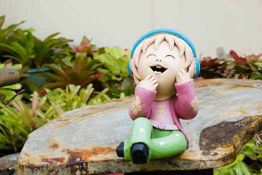 Smiling ceramic doll sit  on the wood table.