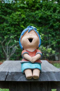 Laughing clay doll sit on the wooden chair