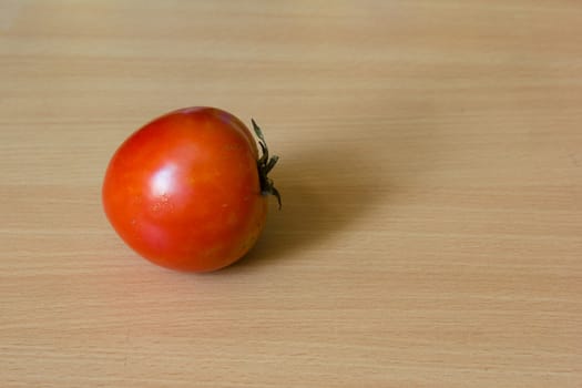 A side-view of fresh tomato on the wooden table.