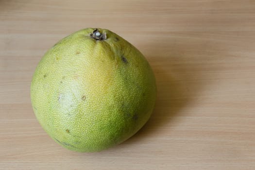 A fresh pomelo on the wooden desk.