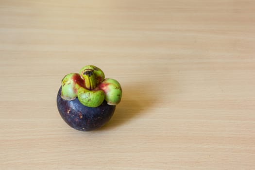 A fresh mangosteen place on a wooden table.
