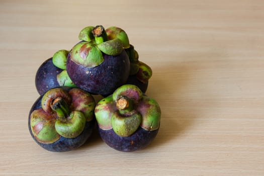 Heap of fresh mangosteen place on a wooden table.