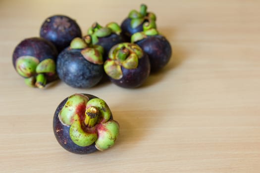 Pile of fresh mangosteen place on a wooden table.