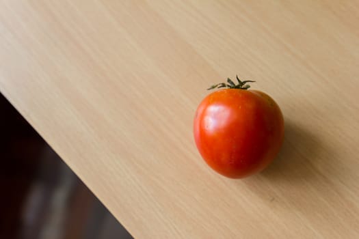 A fresh tomato on the wooden table.