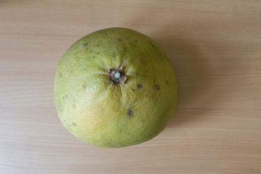 A fresh pomelo on the wooden desk.