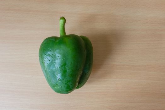 Green pepper (top view) on the wooden desk