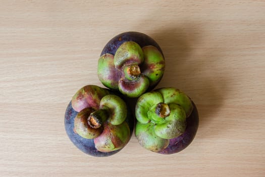 Pile of fresh mangosteen place on a wooden table.