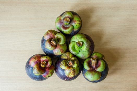 Pile of fresh mangosteen place on a wooden table.
