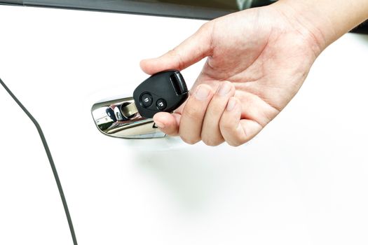 Hand on car key in the car door hole.
