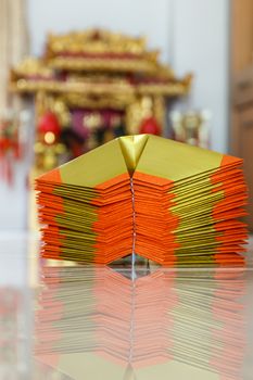 Chinese paper art use for worship.And a shrine in the background.Focus on the top paper.