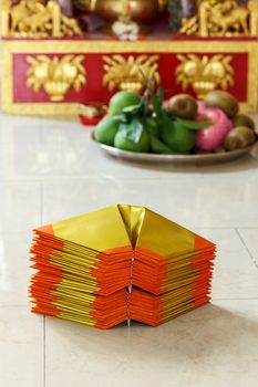 Chinese paper art use for worship.And a shrine in the background.Focus on the top  paper.