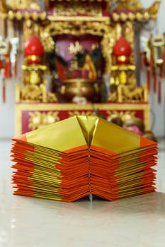 Chinese paper art use for worship.And a shrine in the background.Focus on the top paper.