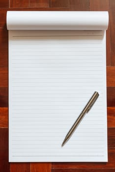 Notebook blank white page. Wooden floor in the background.