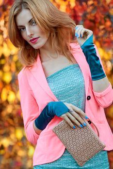 Fashion urban beauty people, woman, outdoor.Playful glamor hipster redhead girl in stylish vivid jacket, gloves with trandy clutch. Sunny day, autumn orange bokeh.Creative unusual, park, lifestyle