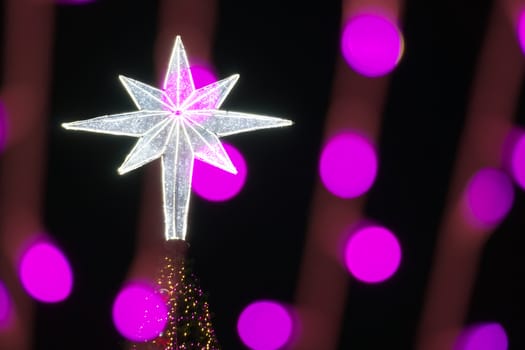 Star on Christmas tree and defocused of glitter or purple bokeh circle at night as background.