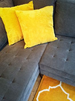Gray corner sofa decorated with bright yellow cushions.