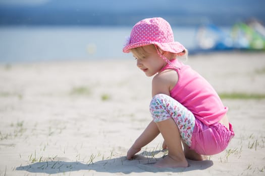 Young blond girl playing in the sand on a beach