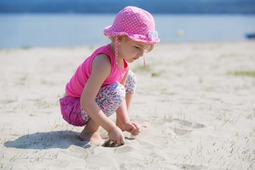 Young blond girl playing in the sand on a beach