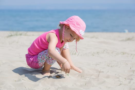 Young blond girl playing in the sand on a beach
