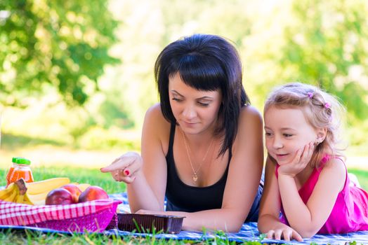 Mom showing her daughter at a picnic fruit