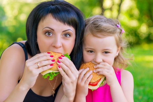 portrait of mother with her daughter in the park with burgers