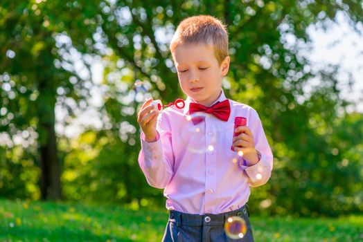 a boy in a green park blowing soap bubbles