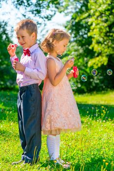 Vertical shot of children 6 years of age with soap bubbles on nature