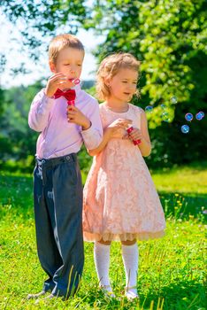 girl and boy with soap bubbles in the park