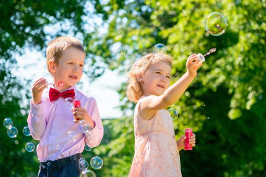 sister and brother in the park with soap bubbles