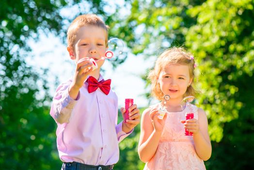 little friends in the summer park with soap bubbles