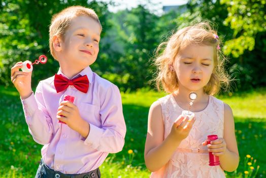 two children in a park with soap bubbles in the hands
