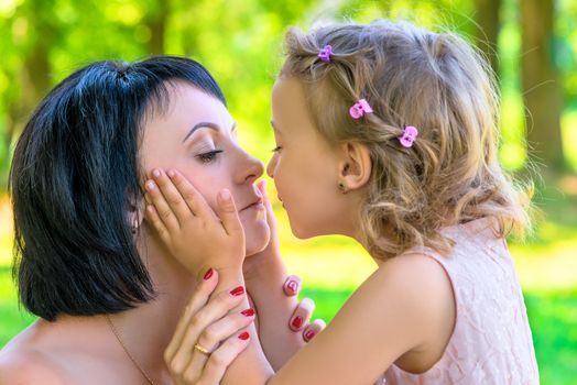 Daughter holds the face of his mother and kisses closeup