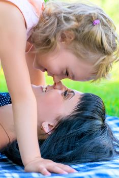 Mother and daughter playing in the summer park face-to-face