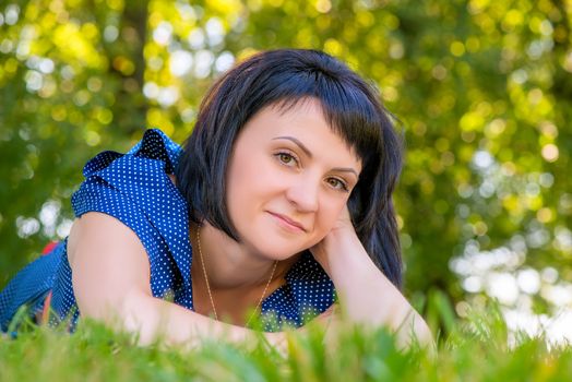 a beautiful young woman lying on the green grass in the park