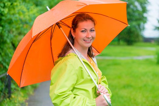 30-year-old smiling girl holding an umbrella under the rain