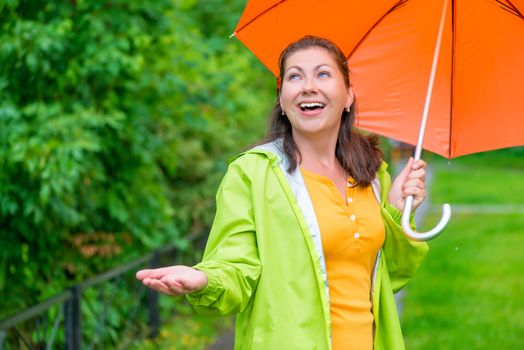 happy young woman with a bright umbrella waiting for the end rain