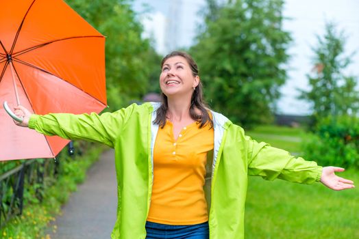 happy young woman enjoying the summer rain in the park