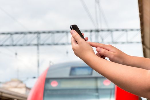 hands close-up with a mobile phone at railway station