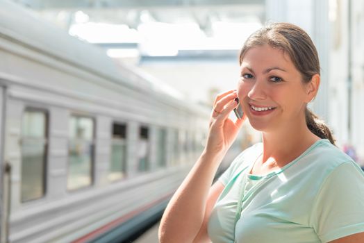 Happy brunette with mobile phone at the station