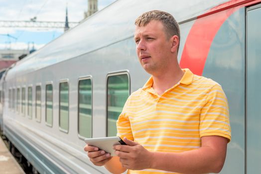 middle-aged man with a tablet beside the train
