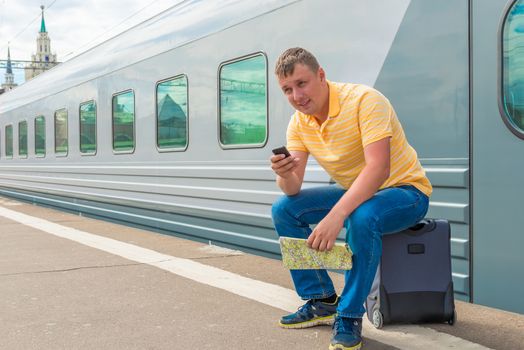 man sitting on a suitcase at the railway station
