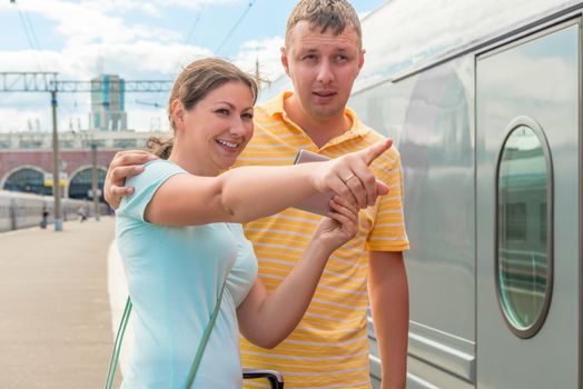 girl shows her husband the direction of the train station